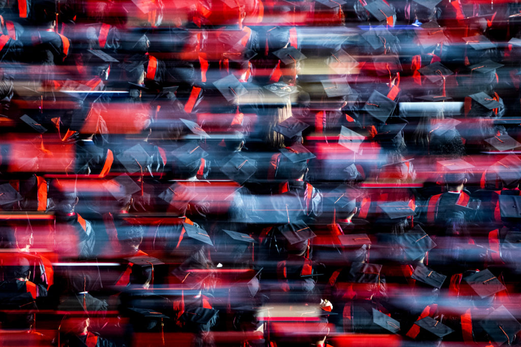 A multiple exposure photo of northeastern students in graduation caps and gowns.